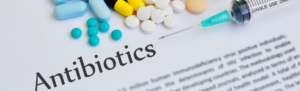 Image with a variety of pills, a syringe, and the word antibiotics