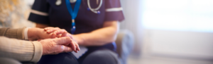 Healthcare worker holding the hand of an elderly resident.