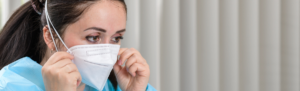 A female healthcare worker putting on a medical mask.