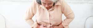 Elderly woman clutching stomach in pain.