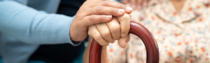 Care giver placing hand on elderly woman's hand.