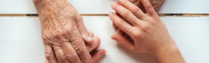 Younger person placing hands over an elderly person's hands.
