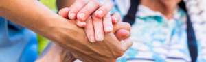 Senior care staff holding resident's hand.
