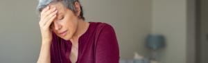 Elderly woman holding her head in stress