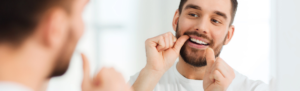 Image of man flossing in the mirror.