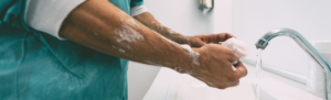 Medical professional washing hands in sink.