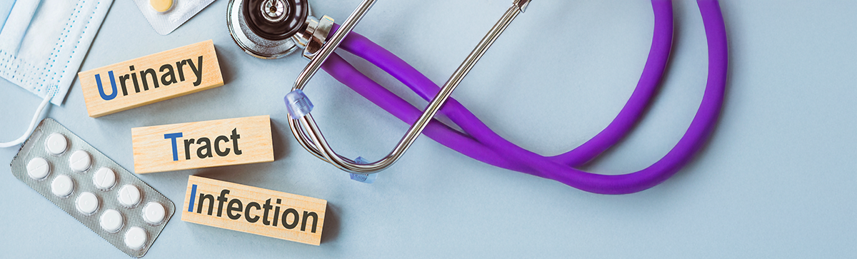 Medication, a stethoscope,, and mask on a blue background with the words Urinary Tract Infection on wooden blockis