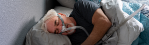Elderly man sleeping with a CPAP machine.
